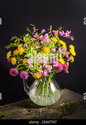 Bouquet luxuriant de fleurs sauvages dans un vase sur fond noir dans le style sombre, encore la vie Banque D'Images