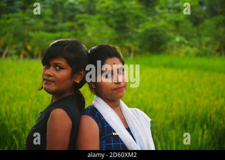 Près de deux adolescentes portant des robes indiennes colorées de salwar kameez dans un champ de paddy vert du Bengale occidental, concentration sélective Banque D'Images