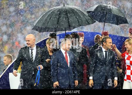 (De gauche à droite) le président de la FIFA, Gianni Infantino, le président russe, Vladimir Poutine et le président français, Emmanuel Macron, se rangent à l'abri de la pluie avant la présentation du trophée Banque D'Images