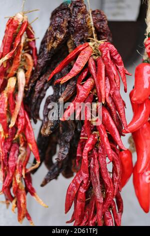 Bouquet de poivrons rouges de lanterne au piment. Une pile de poivrons rouges est suspendue sur un stand de marché. Poivron rouge séché accroché au mur Banque D'Images