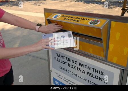 Los Angeles, CA / USA - 14 octobre 2020: Une femme met un bulletin de vote pour l'élection présidentielle de 2020 dans une boîte de scrutin officielle dans L.A. Comté. Banque D'Images