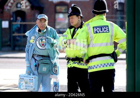 Le fan de Manchester City « Pete the badge » parle à la police à l'extérieur le stade avant le début du match Banque D'Images