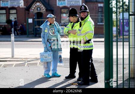 Le fan de Manchester City « Pete the badge » parle à la police à l'extérieur le stade avant le début du match Banque D'Images