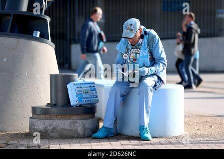 Le fan de Manchester City « Pete the badge » regarde un match programme à l'extérieur du stade avant le début du correspondance Banque D'Images