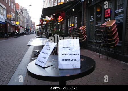 Un panneau « attendez d'être assis » sur les tables vides du restaurant fermé dans le contexte de la pandémie du coronavirus le 14 octobre 2020 à Amsterdam, pays-Bas. Le gouvernement néerlandais a annoncé qu'à partir d'aujourd'hui, de nouvelles mesures plus strictes pour tenter de contrôler les nouvelles infections. Les ventes d'alcool seront interdites après 8 heures et les résidents seront limités à trois personnes par jour maximum à la maison. Tous les cafés, bars et restaurants devront fermer   heures et les masques sont obligatoires dans tous les espaces publics intérieurs. (Photo de Paulo Amorim/Sipa USA) Banque D'Images