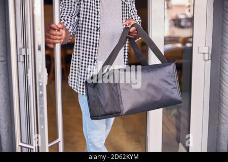 Afro-américain avec sac de livraison de nourriture sortant de café Banque D'Images