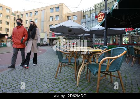 Amsterdam, pays-Bas. 14 octobre 2020. Un couple passe devant des tables vides des restaurants au milieu de la pandémie du coronavirus le 14 octobre 2020 à Amsterdam, pays-Bas. Le gouvernement néerlandais a annoncé qu'à partir d'aujourd'hui, de nouvelles mesures plus strictes pour tenter de contrôler les nouvelles infections. Les ventes d'alcool seront interdites après 8 heures et les résidents seront limités à trois personnes par jour maximum à la maison. Tous les cafés, bars et restaurants devront fermer   heures et les masques sont obligatoires dans tous les espaces publics intérieurs. (Photo de Paulo Amorim/Sipa USA) Credit: SIPA USA/Alay Live News Banque D'Images