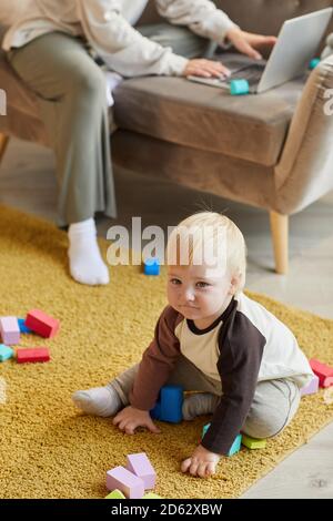Bébé garçon mignon assis sur le sol et jouant avec blocs colorés dans la chambre Banque D'Images