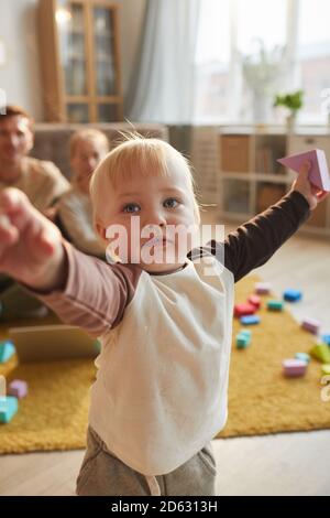 Bébé garçon mignon jouant dans la chambre avec ses parents assis en arrière-plan Banque D'Images