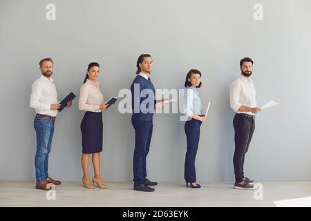 Candidats avec CV en mains alignés dans le couloir en attente d'un entretien Banque D'Images