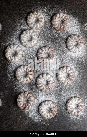 Biscuits Sweet Rings. Biscuits au goût de cacao saupoudrés de sucre sur table noire. Vue de dessus. Banque D'Images