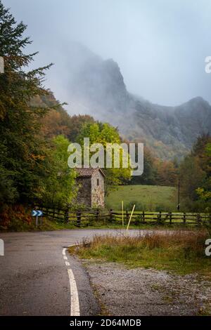 Le brouillard descend la montagne et menace de couvrir la maison et la route. Banque D'Images