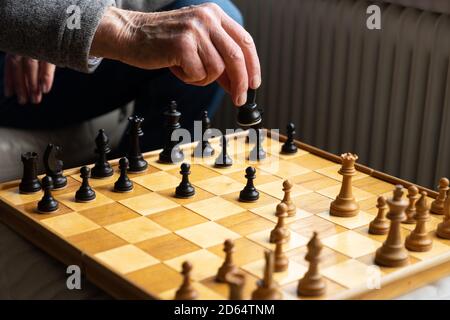 Une partie d'échecs en cours de jeu, vue sur le plateau avec une partie d'un homme méconnaissable en déplaçant une pièce avec sa main Banque D'Images