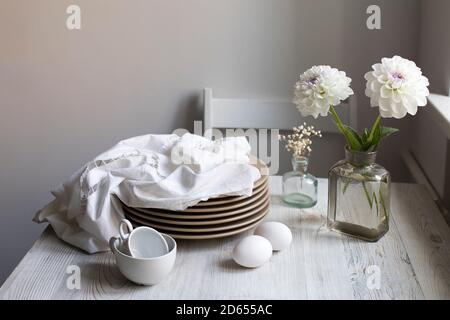 Deux fleurs de dahlia blanches dans une bouteille pharmaceutique au lieu d'un vase. Boîte en bois pour le stockage des bouteilles avec de petits flacons décoratifs dans la cuisine grise Banque D'Images