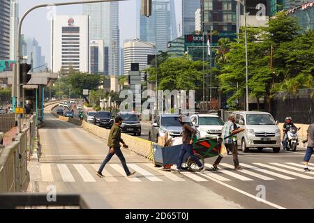 Jakarta / Indonésie - 5 septembre 2020. Un homme traversant par un passage de zébra avec plusieurs voitures à côté de lui est arrêté. Banque D'Images