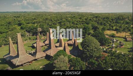 Maisons traditionnelles indonésiennes dans une forêt tropicale avec des toits uniques vue aérienne. Authentique point de repère de l'architecture locale le jour d'été de l'île de Sumba, Nusa Tenggara, Asie. Tir de drone cinématographique Banque D'Images