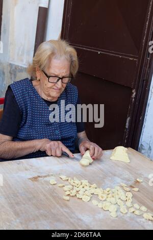 Femme qui fait des pâtes (Orecchiette) à partir de pâte dans la vieille ville de Bari, en Italie Banque D'Images