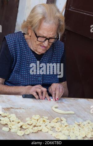 Femme qui fait des pâtes (Orecchiette) à partir de pâte dans la vieille ville de Bari, en Italie Banque D'Images