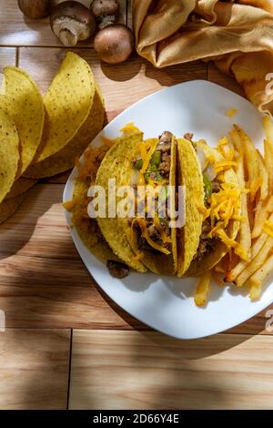 Cuisine mexicaine-américaine de Philly Cheesesteak tacos avec oignons poivrons et champignons, frites sur le côté Banque D'Images