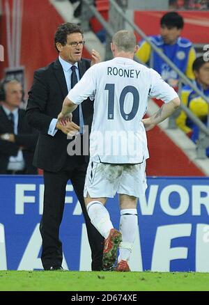 Fabio Capello, directeur de l'Angleterre, donne des indications pour se rendre à Wayne Rooney (r) sur la ligne tactile Banque D'Images