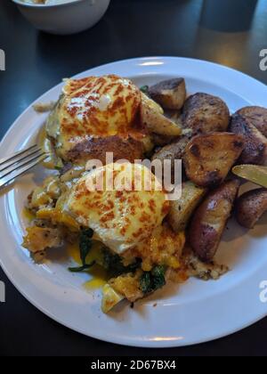 Délicieux repas d'œufs pochés sur un petit pain et rôtis pommes de terre Banque D'Images