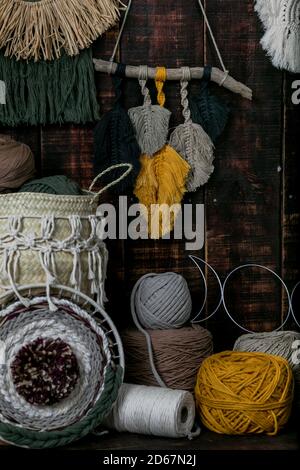 Tir vertical de paniers remplis de balles de laine à tricot multicolore et de macrame accroché au mur Banque D'Images