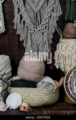 Tir vertical de paniers remplis de balles de laine à tricot multicolore et de macrame accroché au mur Banque D'Images