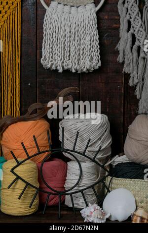 Tir vertical de paniers remplis de balles de laine à tricot multicolore et de macrame accroché au mur Banque D'Images