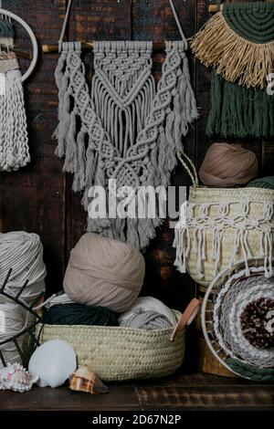 Tir vertical de paniers remplis de balles de laine à tricot multicolore et de macrame accroché au mur Banque D'Images