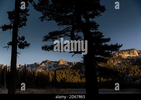 12 juin 2014, Mammoth Lakes, Californie, États-Unis : pins et montagnes enneigées au lac Mary au coucher du soleil, Mammoth Lakes. La Sierra abrite trois parcs nationaux, vingt zones sauvages et deux monuments nationaux. La Sierra Nevada est la plus haute chaîne de montagnes des États-Unis contigus. Mammoth Lakes se trouve au bord de la Caldera de la vallée de long et est géologiquement active. Les points forts sont la station de ski de Mammoth Mountain, au-dessus du sommet de Minaret, puis jusqu'au monument national Devils Postpile, avec accès à la région sauvage d'Ansel Adams. La région a des sources chaudes naturelles, des lacs, des sources de soda Banque D'Images