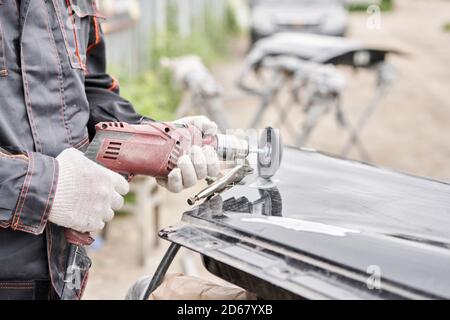 Réparation de la carrosserie, application PuTTY gros plan. Le mécanicien répare la voiture. Travailler après l'accident en travaillant le primaire de ponçage avant de peindre. Banque D'Images