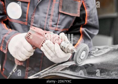 Réparation de la carrosserie, application PuTTY gros plan. Le mécanicien répare la voiture. Travailler après l'accident en travaillant le primaire de ponçage avant de peindre. Banque D'Images