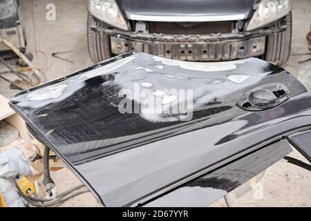 Réparation de la carrosserie, application PuTTY gros plan. Le mécanicien répare la voiture. Travailler après l'accident en travaillant le primaire de ponçage avant de peindre. Banque D'Images