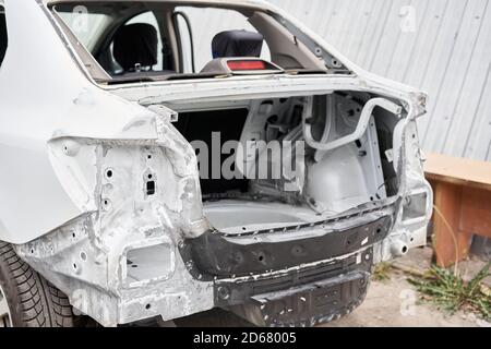 Réparation de la carrosserie, application PuTTY gros plan. Le mécanicien répare la voiture. Travailler après l'accident en travaillant le primaire de ponçage avant de peindre. Banque D'Images