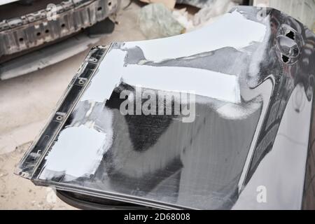 Réparation de la carrosserie, application PuTTY gros plan. Le mécanicien répare la voiture. Travailler après l'accident en travaillant le primaire de ponçage avant de peindre. Banque D'Images