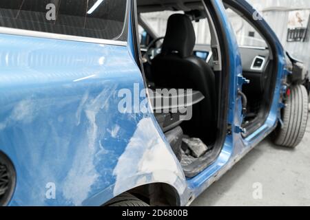 Réparation de la carrosserie, application PuTTY gros plan. Le mécanicien répare la voiture. Travailler après l'accident en travaillant le primaire de ponçage avant de peindre. Banque D'Images