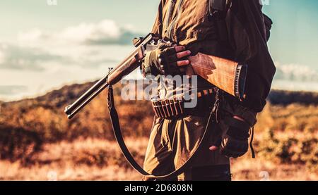 Chasseur avec un fusil de chasse et une forme de chasse pour chasser dans une forêt d'automne. L'homme est sur le hun Banque D'Images