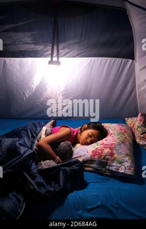 Petite fille métis dormant bien dans une tente de camping pendant les vacances. Banque D'Images