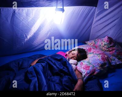 Petite fille métis dormant bien dans une tente de camping pendant les vacances. Banque D'Images