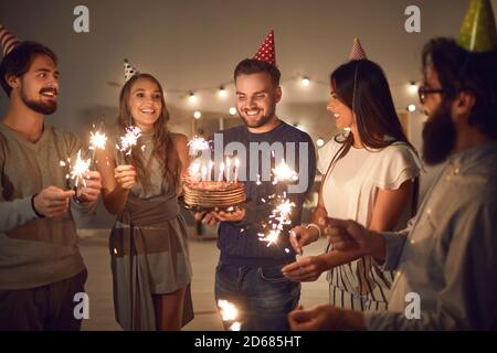 Groupe de jeunes heureux avec des sparklers célébrant leur ami anniversaire à la maison Banque D'Images