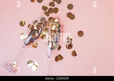 Confettis dorés dans des verres à champagne sur fond de couleur pêche Banque D'Images