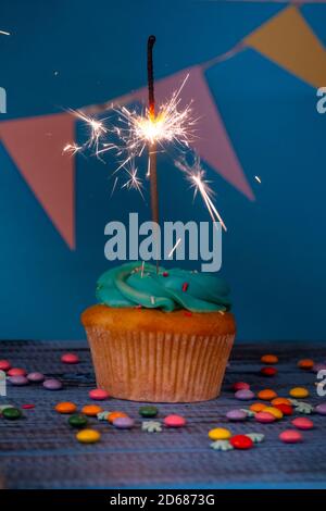 Gâteau d'anniversaire ou de noël avec un peu de sparkler, sur fond bleu, tons foncés, mise au point sélective Banque D'Images