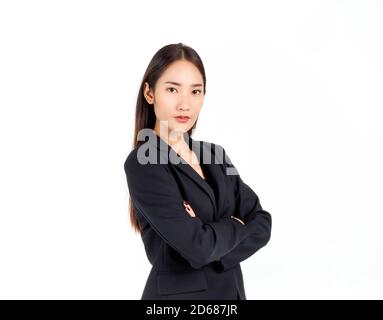 Une jeune femme d'affaires asiatique confiante en costume noir, debout avec ses bras repliés et regardant la caméra isolée sur fond blanc. Banque D'Images