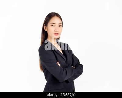 Une jeune femme d'affaires asiatique confiante en costume noir, debout avec ses bras repliés et regardant la caméra isolée sur fond blanc. Banque D'Images