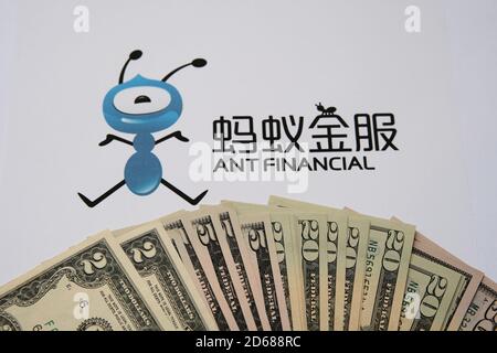 Pile de billets en dollars répartis sur un document avec le logo flou du groupe Ant Financial sur l'arrière-plan. Banque D'Images