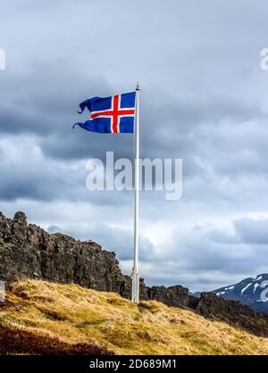 Le drapeau de l'Islande flotte dans le vent sur le fond bleu sombre du ciel. Banque D'Images