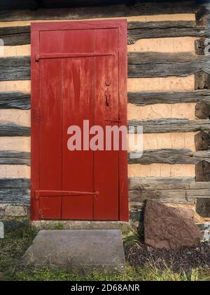 Porte rouge dans une cabane coloniale en rondins de Pennsylvanie. Banque D'Images