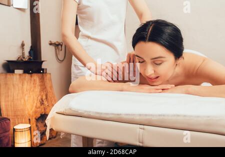 Magnifique brunette bénéficiant d'un massage du dos dans un salon spa oriental. Massage corporel thaïlandais Banque D'Images