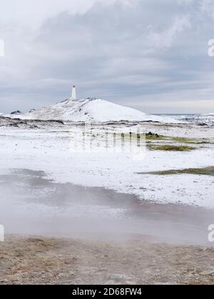 Phare de Reykjanviti avec de la vapeur survolant les sources chaudes de la zone géothermique Gunnuhver et la centrale géothermique de Teh Sudurnes. europe, non Banque D'Images