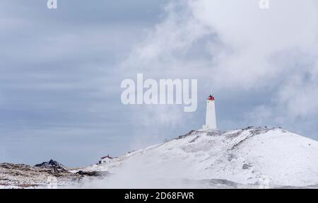 Phare de Reykjanviti avec de la vapeur survolant les sources chaudes de la zone géothermique Gunnuhver et la centrale géothermique de Teh Sudurnes. europe, non Banque D'Images